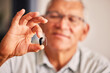 © Theron/peopleimages.com - Hand holding hearing aid, senior man and tech for ears, health and wellness for retirement in nursing home. Elderly person with disability, audio or sound technology to listen in closeup at house