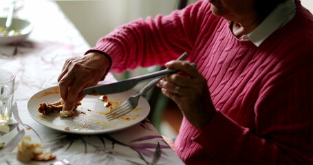 senior woman finishing lunch cleaning plate with bread leftovers