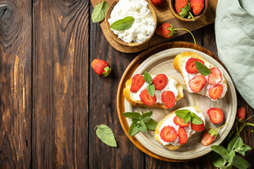 Wall Mural - Berries toast breakfast, healthy food. Sandwich with strawberries and soft cheese on wooden background. View from above. Copy space.