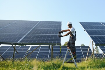 portrait of african american electrician engineer in safety helmet and uniform installing solar pane