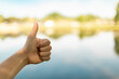 © kieferpix - thumbs up gesture by a tranquil lake nature setting