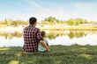 © kieferpix - Bonding family father and child sitting by tranquil lake, surrounded by nature's beauty