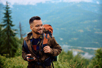 happy backpacker smart phone hiking in nature on rainy day.