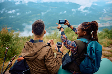 Multiracial couple of hikers enjoy in view from top of hill.