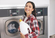© Prostock-studio - Lady Holding Detergent Bottle Standing Near Washing Machines At Laundrette