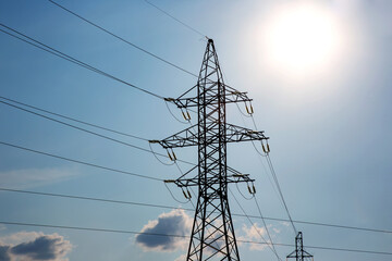 Wall Mural - The concept of a source of electricity. Energy industry. High voltage tower with power wires against the background of the sun and clouds.