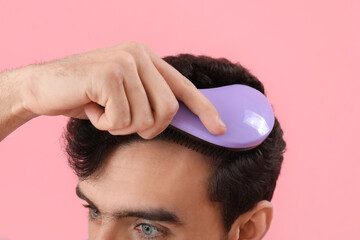 Poster - Young brunette man brushing hair on pink background, closeup