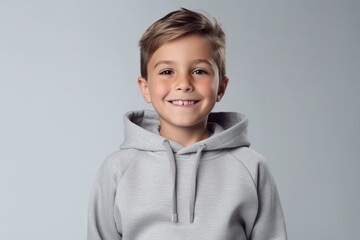 Wall Mural - Portrait of a smiling little boy in a hoodie on a gray background