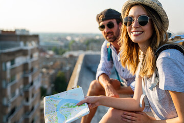 Wall Mural - portrait of young tourists couple with backpacks sightseeing city together on summer vacation.