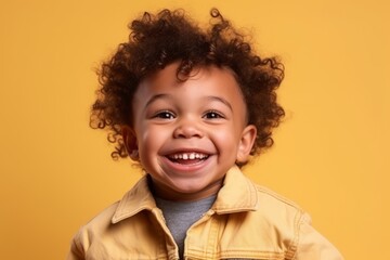 Wall Mural - Portrait of a smiling african american little boy over yellow background