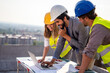 © NDABCREATIVITY - Team of architects people in group on construciton site check documents and business workflow