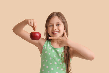 Wall Mural - Little girl pointing at apple on beige background