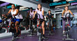 Multiethnic group of young adults training on cycling machines in fitness center