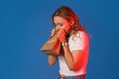 Young woman with paper bag having panic attack on blue background