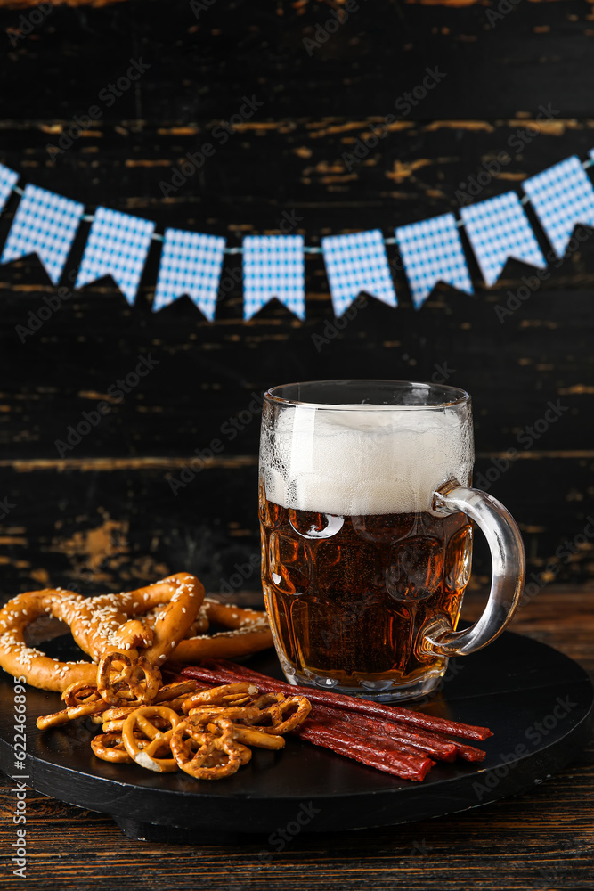 Mug of cold beer and different snacks on wooden background. Oktoberfest celebration