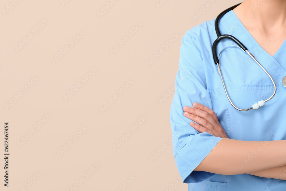 Female doctor with stethoscope on beige background