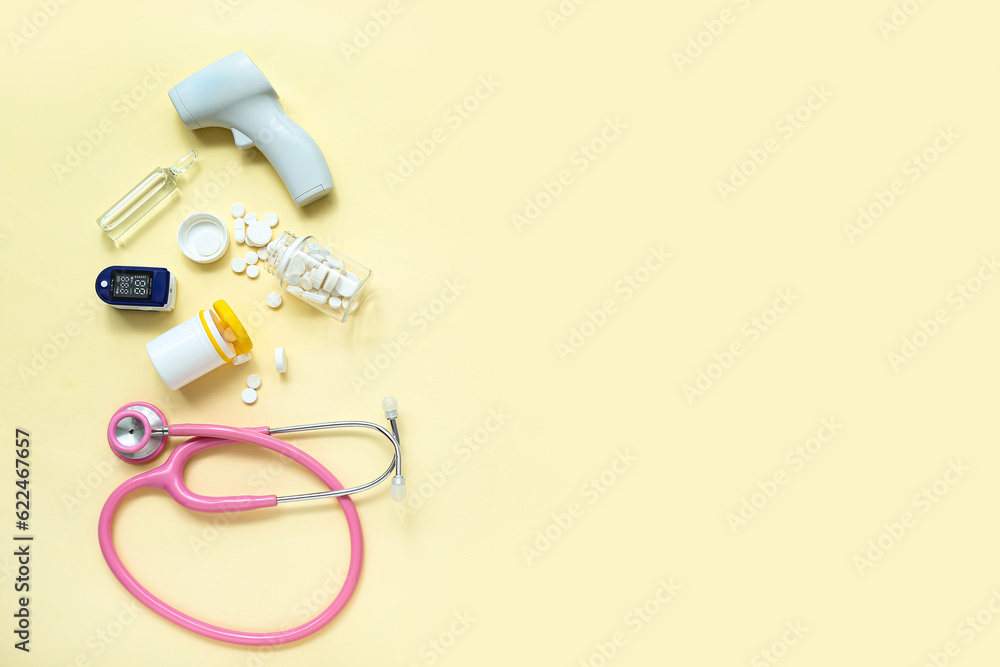 Stethoscope, pills, pulse oximeter, infrared thermometer and ampule on yellow background