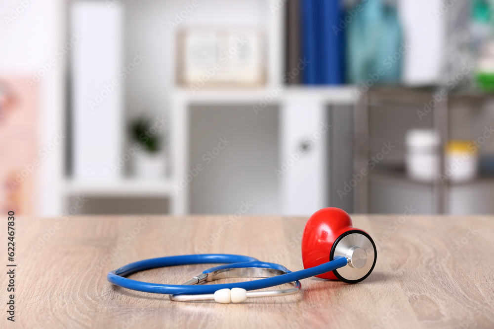 Stethoscope and heart on wooden table in doctor office