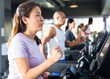 © JackF - Positive girl running on treadmill in fitness club