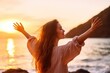 © Adriana - Backlit Portrait of calm happy smiling free woman with open arms and closed eyes enjoys a beautiful moment life on the seashore at sunset