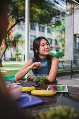 University student eating a salad while taking a break from classes. She is at the college campus.