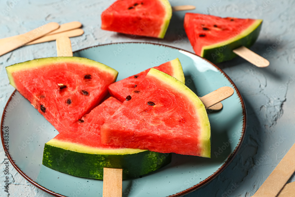 Plate with sweet watermelon sticks on blue background