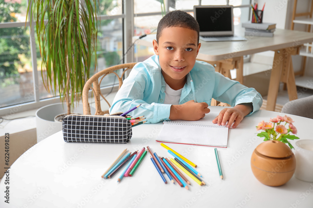 Little African-American boy with pencil case drawing at home