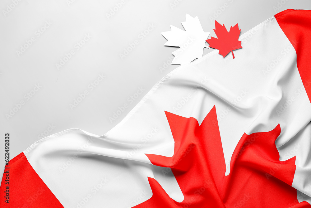 Flag of Canada and paper maple leaves on grey background