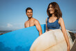© Odua Images - young couple carrying surfboards walking at beach against blue sky enjoying a vacation
