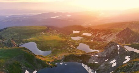Wall Mural - flying over mountain peaks, hills, seven rila lakes and clouds, scenic sunrise light, 4k video of bu