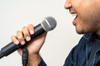 © Chanakon - Close up male hand holding High quality dynamic microphone and singing song or speaking talking with people on isolated white background. Male testing microphone voice for interview