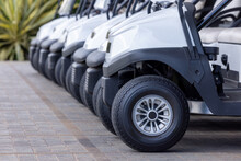  Golf Cars In A Row Outdoors On A Golf Course. A Row Of Empty Golf Carts On A Golf Course. Golf Course Carts Cars At Luxury Resort Sport Venue.All Lined Up Ready For A Tournament On A Course.