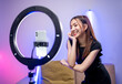 Young trendy influencer asian woman dancing on mobile phone at home in living room with neon light. Creator vlogger talent dancing enjoy hobby content recording show video sharing on social media.
