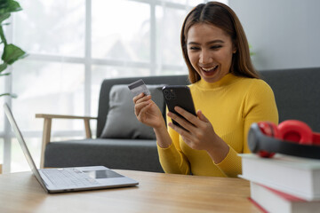 Asian businesswoman shopping online on mobile with credit card for convenient spending at home on vacation, online banking banking, e commerce virtual shopping, secure mobile banking concept.