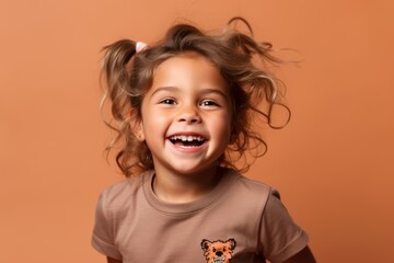 Canvas Print - Portrait of a smiling little girl with flying hair on a brown background