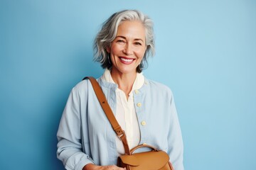 Poster - Portrait of a happy senior woman with handbag on blue background