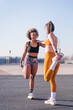 vertical photo of two female multiracial friends stretching together in an urban park, concept of friendship and sportive lifestyle, copy space for text