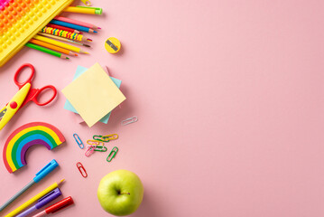 Primary school essentials. Overhead shot of colorful array: sensory fidget case, pencils, sticky memos, paper clips, scissors, rainbow plasticine, and apple. Spacious pastel background for text or ad