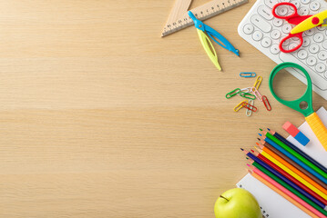 Immerse yourself in the world of education with this top-view photo showcasing a child's workplace with keypad from pc on isolated wooden background, with copy-space for text or advertisements