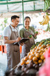 © Odua Images - couple of asian fruit seller checking the fruits and writing on the clipboard