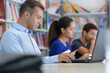 © auremar - adult and teenagers working around table in library