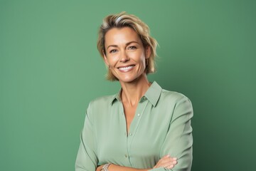 smiling businesswoman with crossed arms looking at camera isolated on green