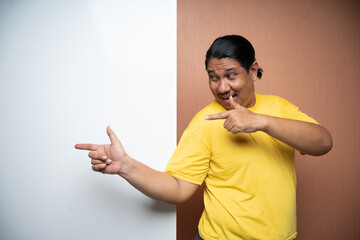 old asian man standing beside empty whiteboard with pointing gesture and looking sideways in plain background isolated