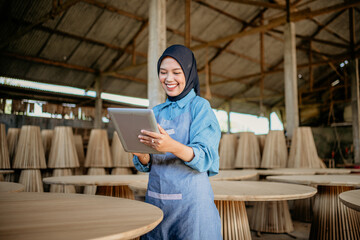 Wall Mural - young businesswoman in veil standing using a tablet to work in wood craft shop