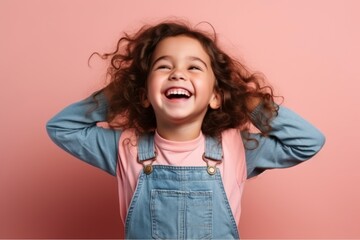 Wall Mural - Portrait of a smiling little girl with curly hair on a pink background