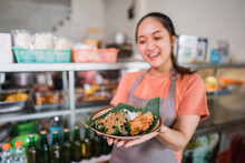 A Plate Of Pecel Cuisine With Banana Leaves Is Shown By Asian Girl In Apron At A Food Stall
