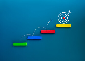 Curved line arrow jumping on colorful stair blocks from below to the target icon on the top block on blue background, minimal style. Business goal and success, growth marketing, and trend concepts.