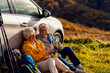 © Zoran Zeremski - Senior couple sitting against the car, resting after hiking in countryside.