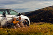 © Zoran Zeremski - Senior couple sitting against the car, resting after hiking in countryside.