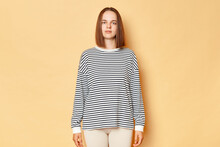Serious Strict Brown Haired Woman Wearing Striped Shirt Standing Isolated Over Beige Background Looking Nat Camera With Bossy Stressed Expression, Being In Bad Mood.
